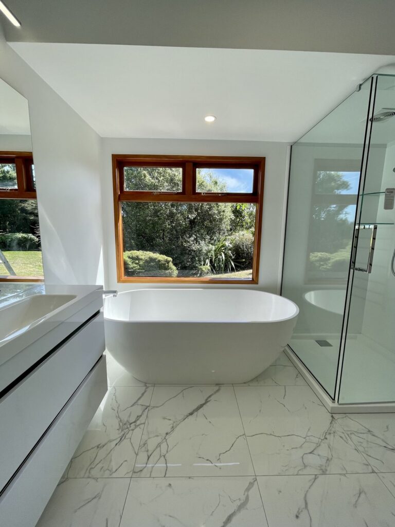 Same bathroom after renovation with freestanding bath and marble look tiles