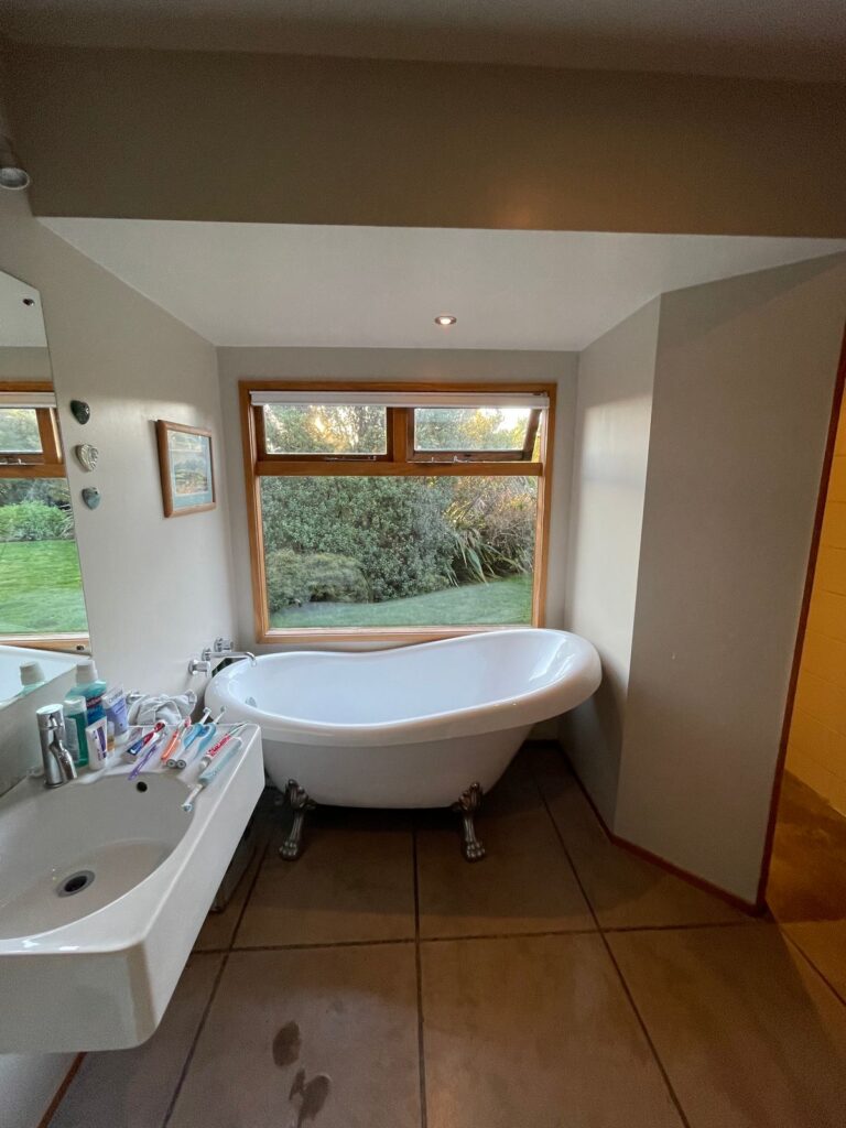 Bathroom before renovation with clawfoot bath and timber window