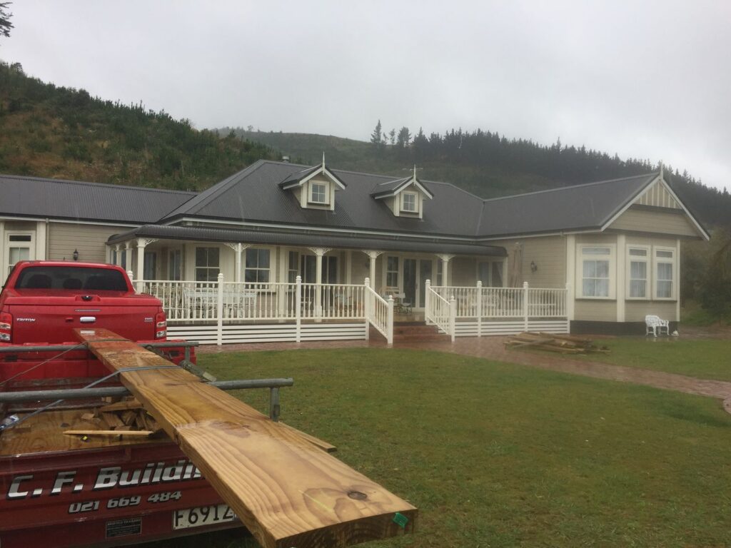 Colonial style home with a white veranda and the Craig Finnie Builders trailer