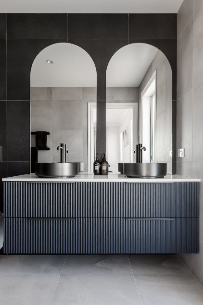 Black and grey bathroom with arched mirrors at Redvale Estate
